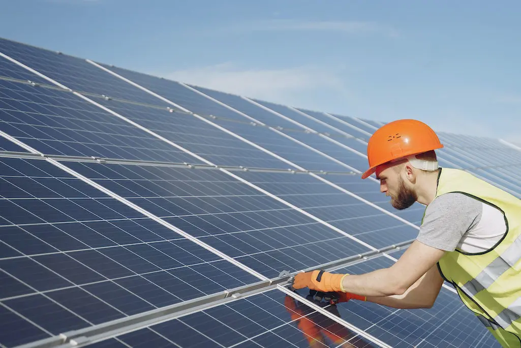 En man som monterar solceller på ett tak.