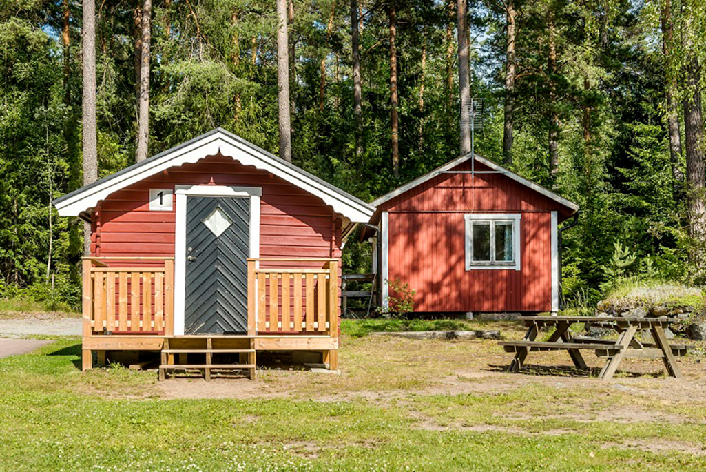 Bild på en liten röd campingstuga.