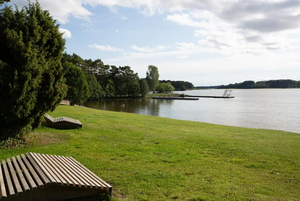 Översiktsbild över Bredsandsstranden. Vatten och gräsmatta.