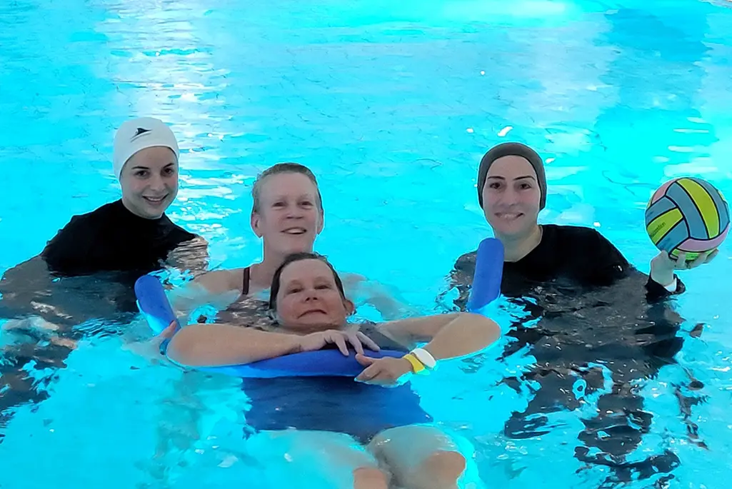 Fyra personer simmar i en bassäng.