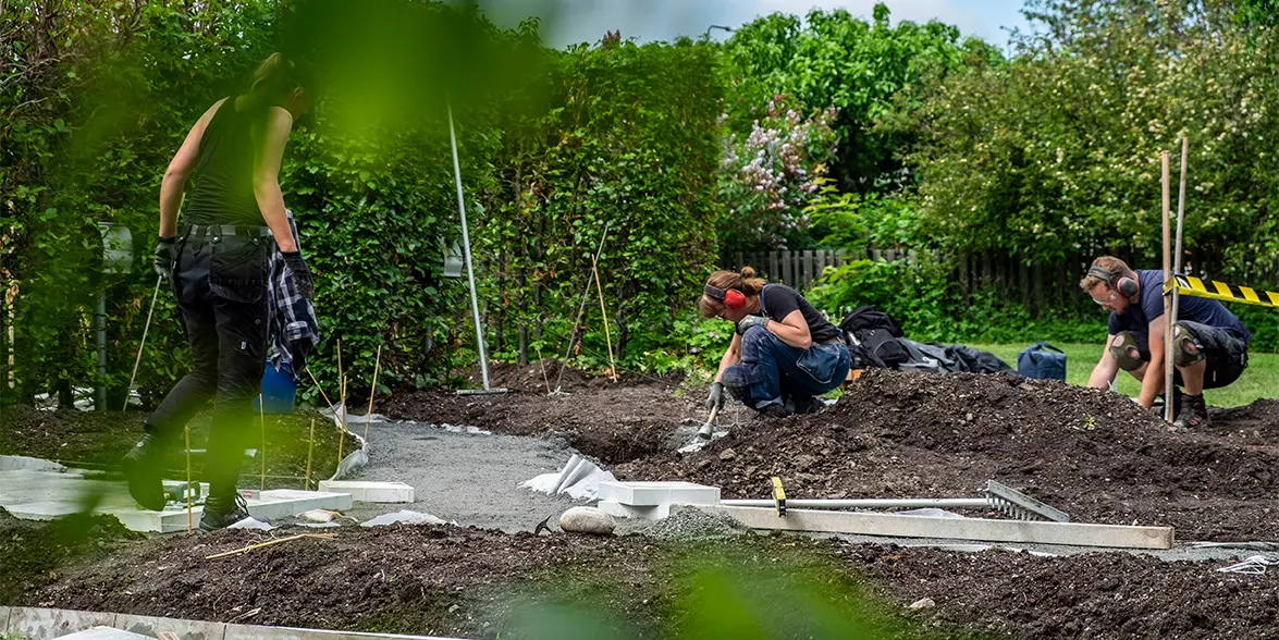 Tre personer gräver i en trädgård