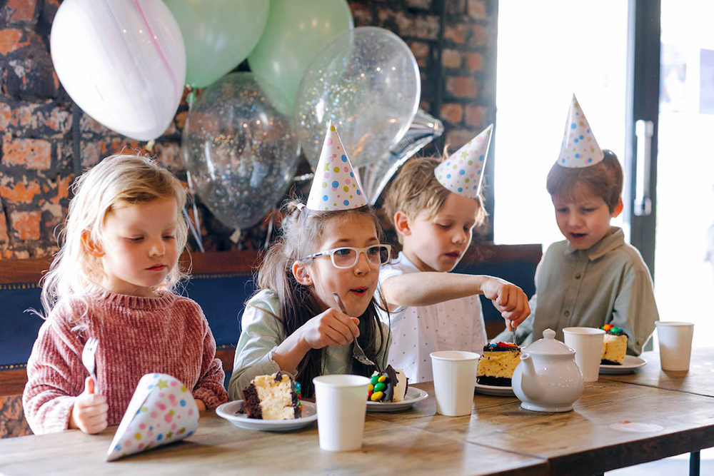 Bild på barn som har ett barnkalas med ballonger och fika.