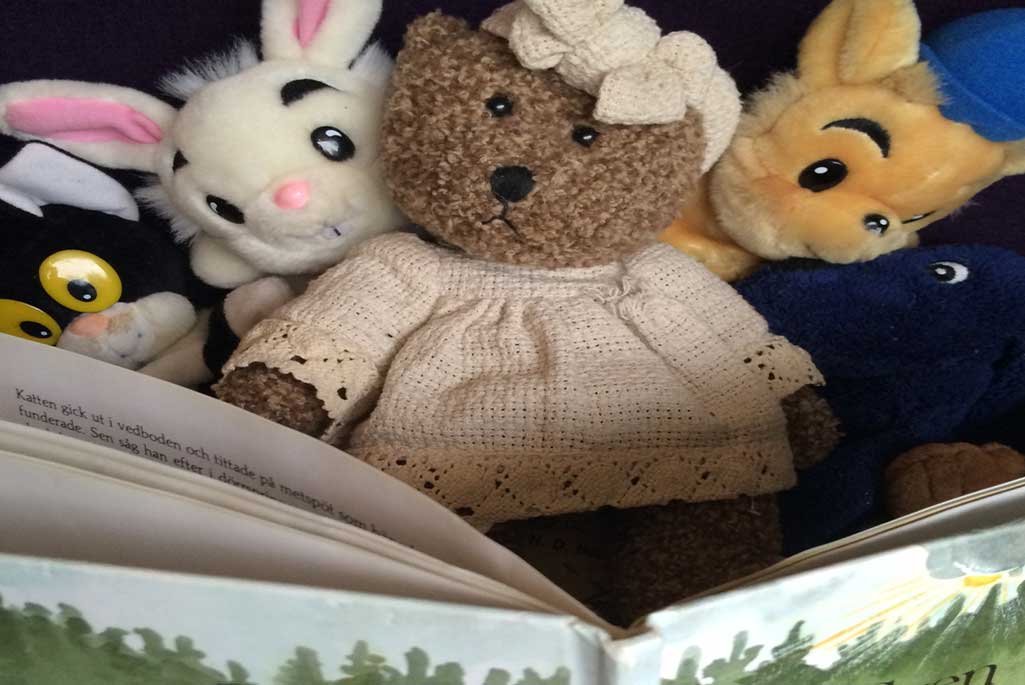 Foto på gosedjur som har en bok placerad framför sig.