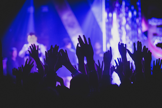 Bild från en konsert där man ser människor som sträcker upp händerna mot skyn.