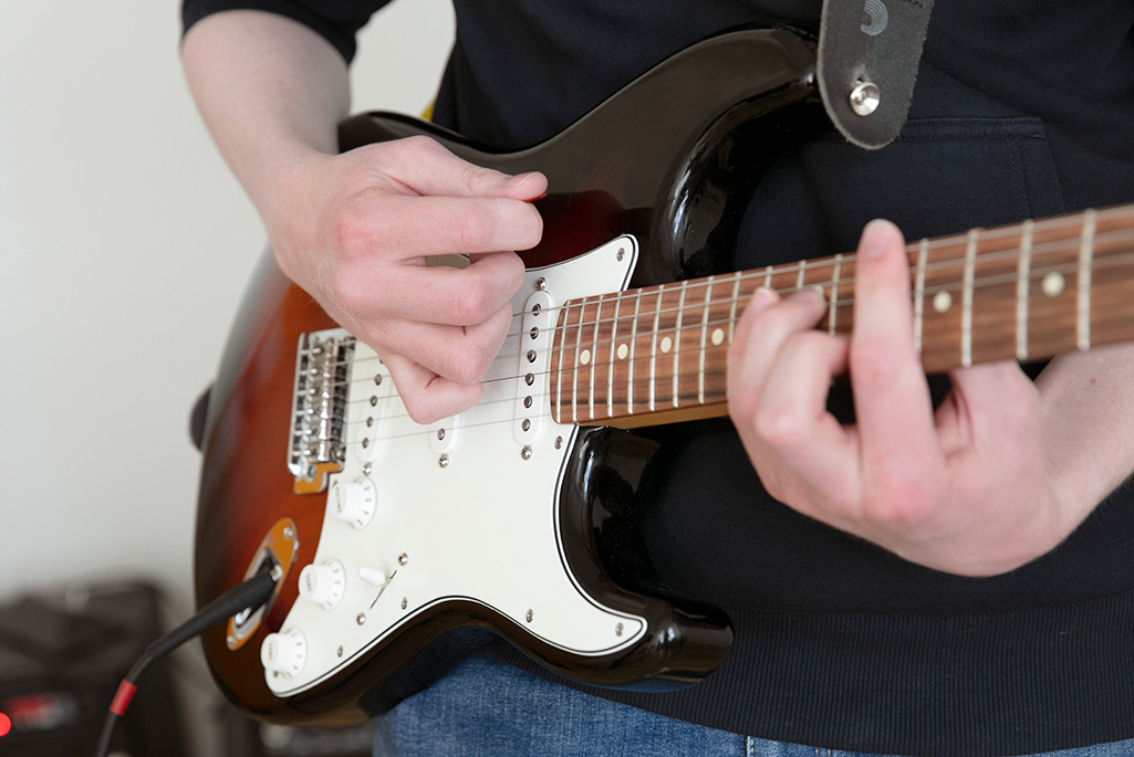 Bild på en person som spelar elgitarr.