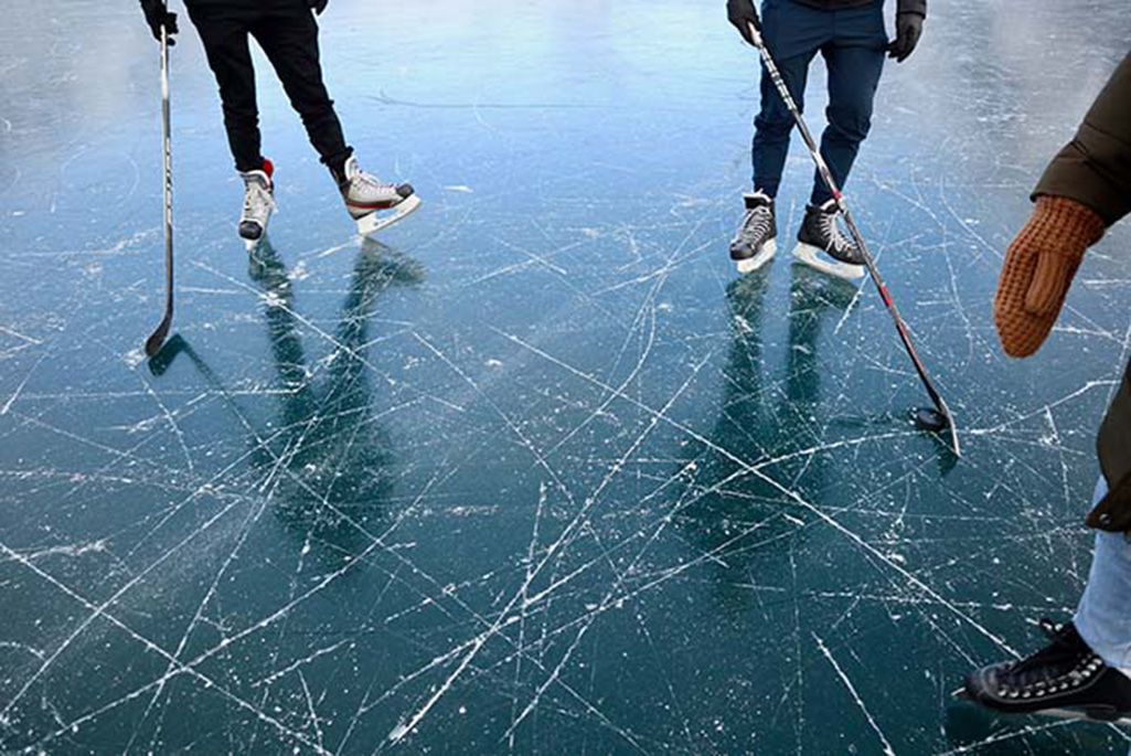 Foto på två personer som åker skridskor på isen med benen i fokus.