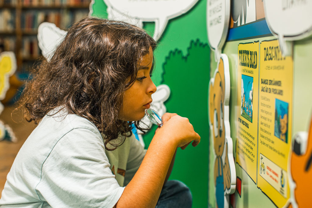 Ett barn som fokuserar på en vägg med affischer i bamses källspanare.