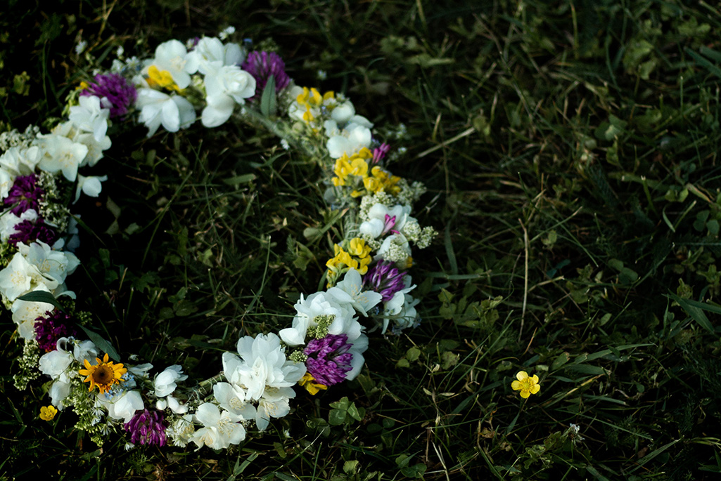 Bild på en krans av blommor som ligger på en gräsmatta.