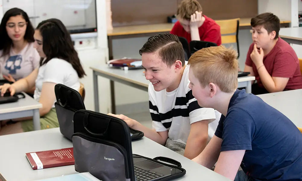 Foto av elever som sitter med laptops i ett klassrum.