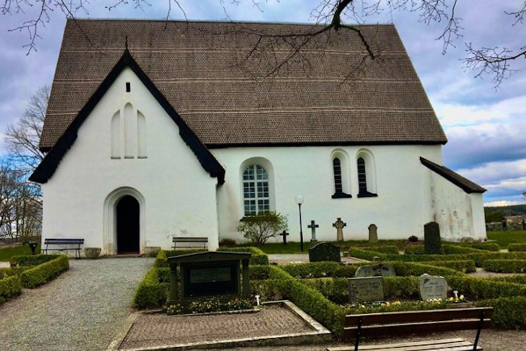 Bild på Härkeberga kyrka. En vit stenbyggnad.