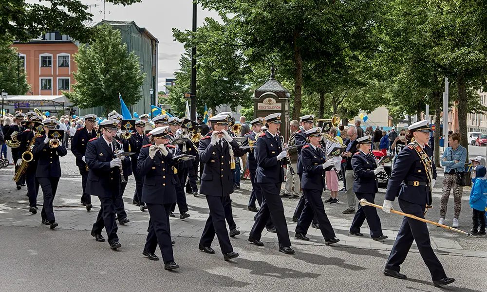 Bild som visar firandet av nationaldagen i Enköping. Det är en orkester som går på en gata.