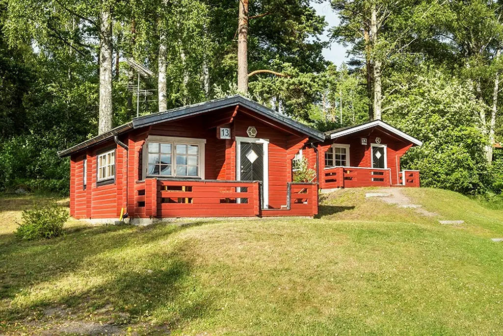 Röd stuga i skogsbrynet