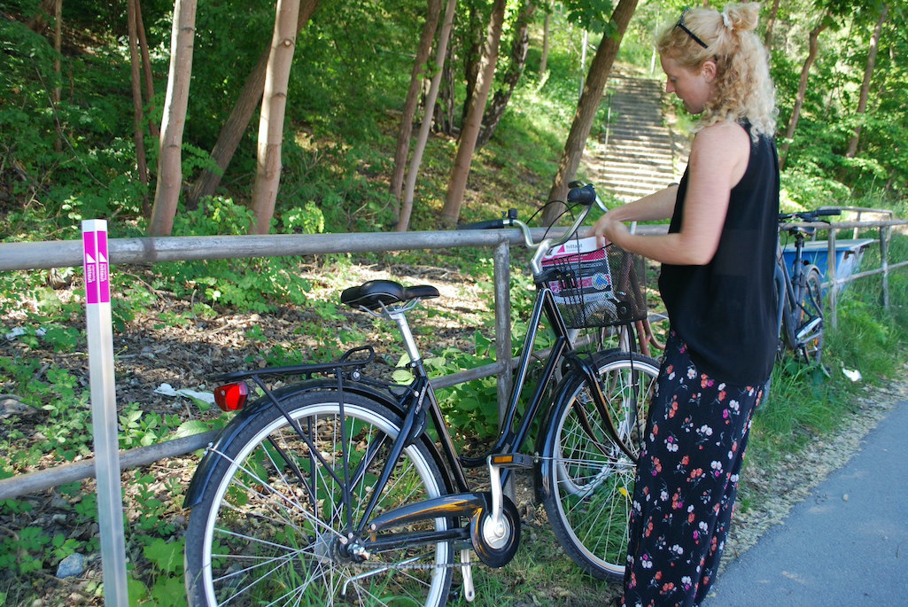 Bild på en tjej och en cykel ute i en skog.