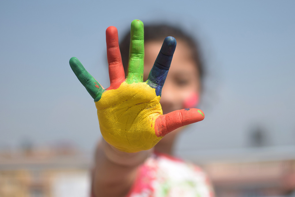 Bild på ett barn som har målat sin hand i olika färger.