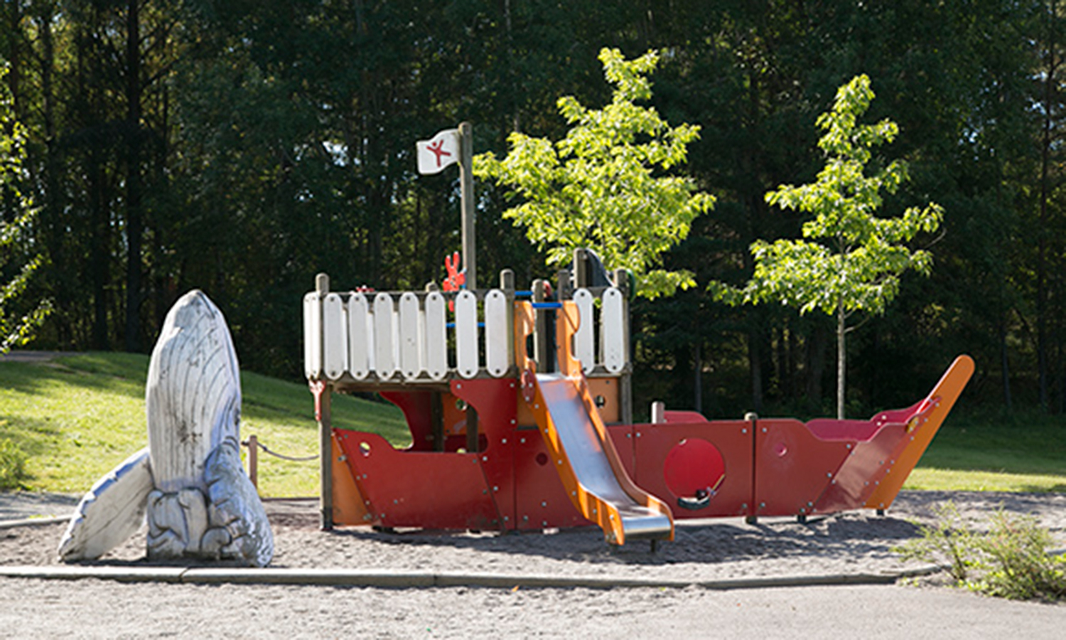 Foto på Skeppets lekplats. Lekplatsen består av en båt och en valfigur i trä.