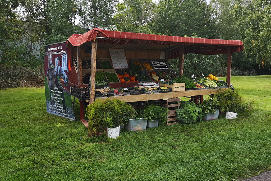 Bild på ett marknadsstånd där det finns många olika grönsaker.