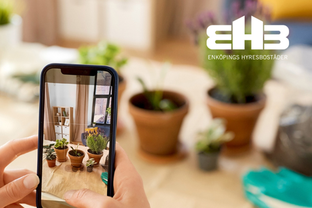 Bild på en en mobil som någon tar en bild på där motivet är tre krukor med växter i.