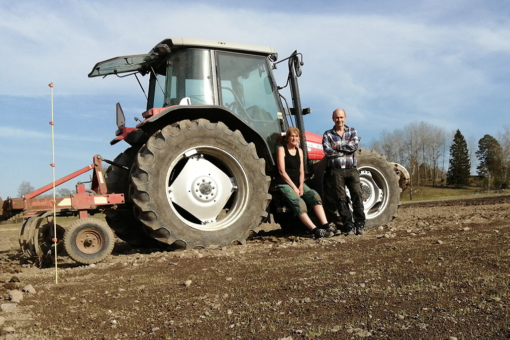 Bild på två personer som står framför en traktor.