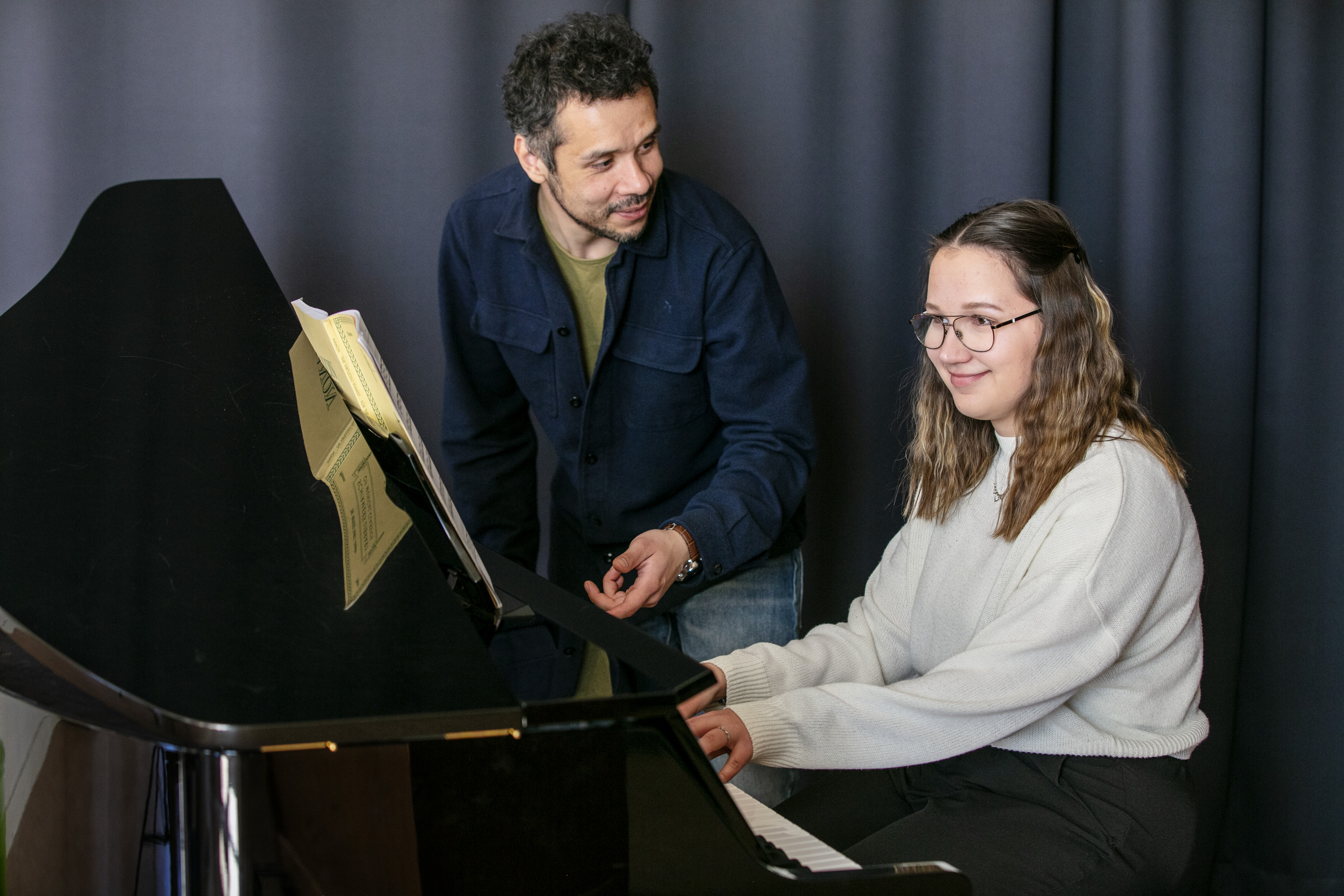 En manlig lärare och tjej spelar piano.