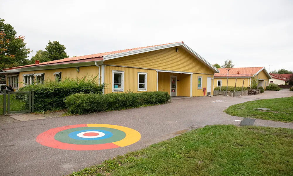 Foto på Gånsta förskola. Det är en gul byggnad med vita knutar.