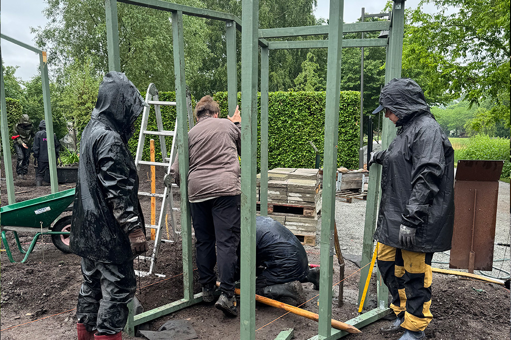 Grön pergola och jordiga rabatter utan växter