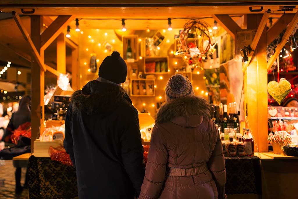 Två personer framför ett stånd på en julmarknad.